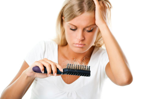 woman looking at the hair brush with a lot of hair falls